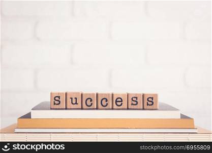 The word Success, alphabet on wooden cubes on top of books. Background copy space, vintage minimal. Ideas for goal resolution, business project, financial management, academic, education concepts.
