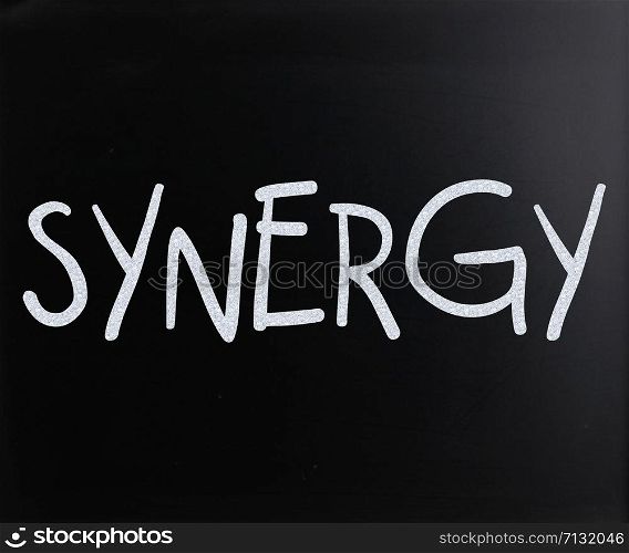 "The word "Synergy" handwritten with white chalk on a blackboard"