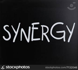 "The word "Synergy" handwritten with white chalk on a blackboard"