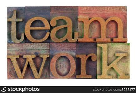 the word teamwork in vintage wooden letterpress type, stained by colorful inks, isolated on white