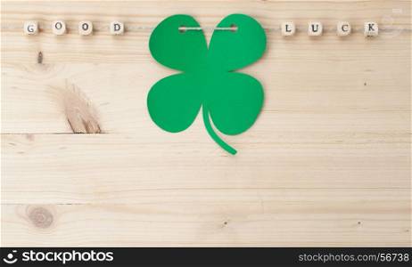 The words Good Luck and a cloverleaf on a cord on wood
