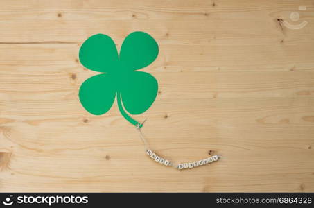 The words Happy Birthday and a cloverleaf on a cord on wood