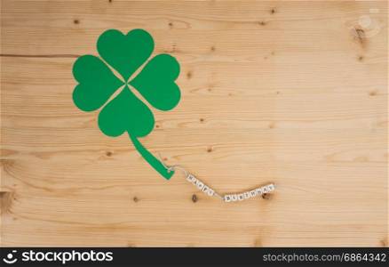 The words Happy Birthday and a cloverleaf on a cord on wood