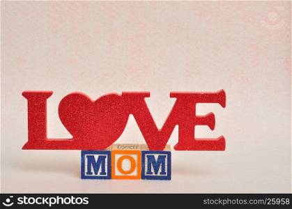 The words love mom spelled with alphabet blocks against a white background