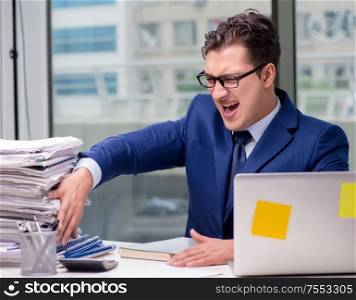 The workaholic businessman overworked with too much work in office. Workaholic businessman overworked with too much work in office