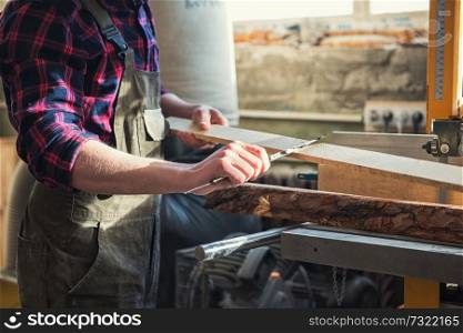 The worker makes measurements of a wooden board with corner ruler.. The worker makes measurements of a wooden board