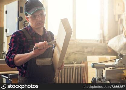 The worker makes measurements of a wooden board with corner ruler. Profession, carpentry and woodwork concept.. The worker makes measurements of a wooden board