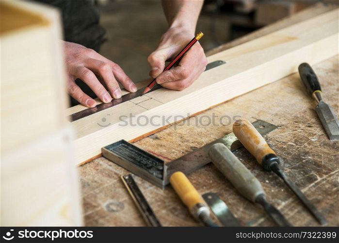 The worker makes measurements of a wooden board with ruler.. The worker makes measurements of a wooden board