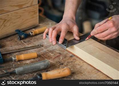 The worker makes measurements of a wooden board with ruler.. The worker makes measurements of a wooden board
