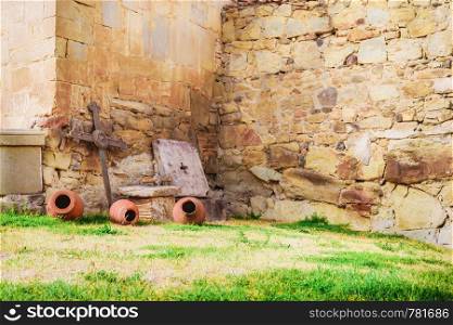 The yard of the ancient monastery with metall cross and clay pots near wall. The yard of the ancient monastery with metall cross and clay pots