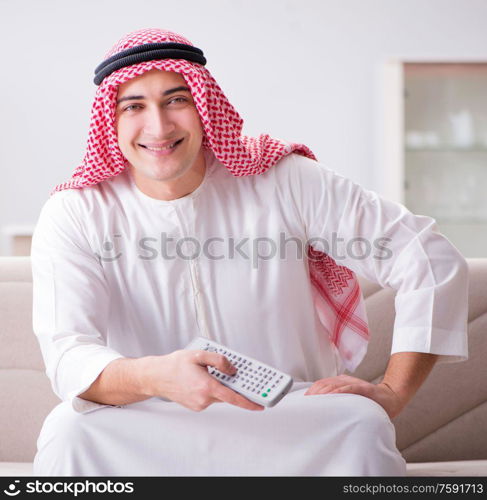 The young arab man watching tv sitting on the sofa. Young arab man watching tv sitting on the sofa