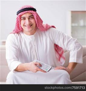The young arab man watching tv sitting on the sofa. Young arab man watching tv sitting on the sofa