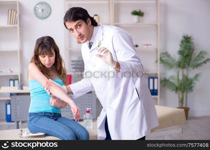 The young arm injured woman visiting young doctor traumatologist. Young arm injured woman visiting young doctor traumatologist