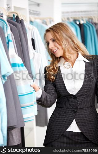 The young attractive girl considers clothes in shop