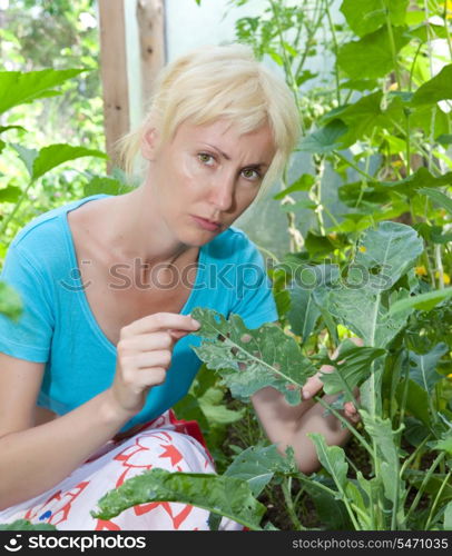 The young attractive woman is upset - caterpillars eat leaves of plants