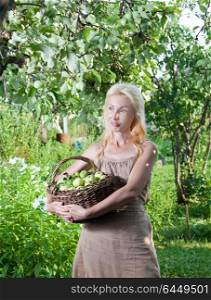 The young attractive woman with a basket of apples in a garden