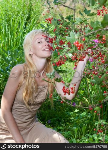 The young beautiful girl near to a bush of a red currant.