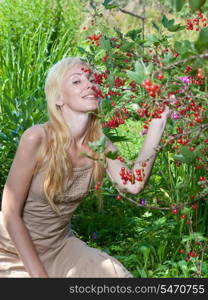 The young beautiful girl near to a bush of a red currant.