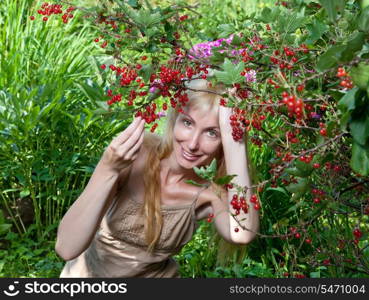 The young beautiful girl near to a bush of a red currant.