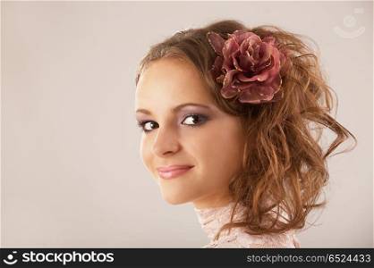 The young beautiful girl poses with a flower in hair. Beauty