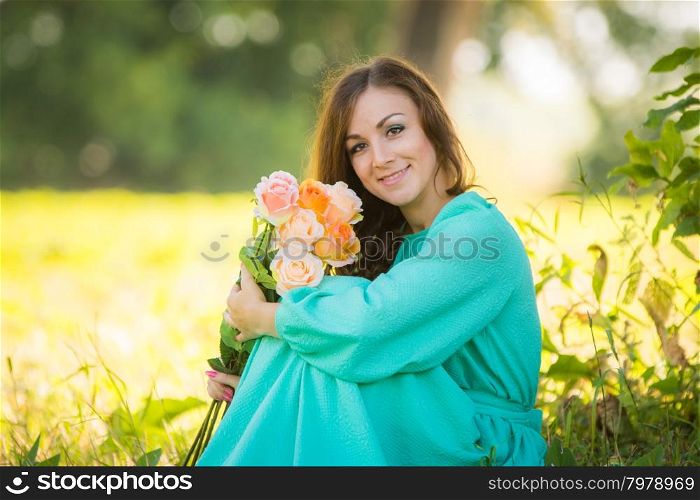 The young beautiful girl walks in autumn forest in warm sunny weather. Portrait of a young girl with a bouquet of roses sitting in the shade of the trees on a sunny day