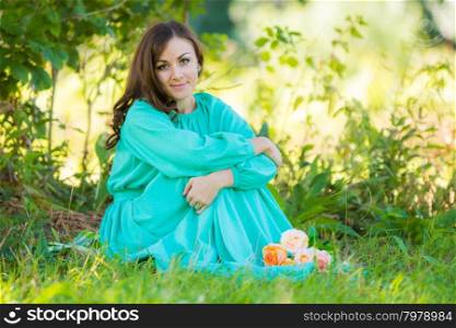 The young beautiful girl walks in autumn forest in warm sunny weather. A girl in a long dress sitting in the shade of the trees on a sunny day