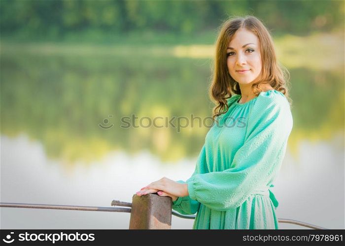 The young beautiful girl walks on an old bridge in the warm autumn weather. Portrait of a girl on the bridge over the river in the early morning