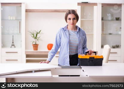 The young beautiful woman assembling furniture at home. Young beautiful woman assembling furniture at home