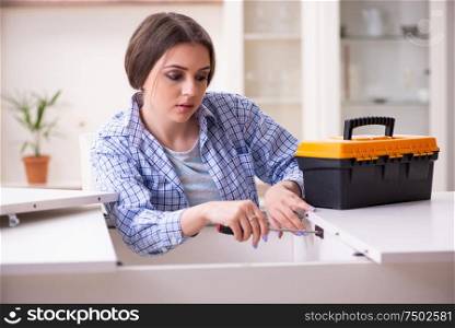 The young beautiful woman assembling furniture at home. Young beautiful woman assembling furniture at home