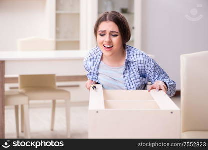 The young beautiful woman assembling furniture at home. Young beautiful woman assembling furniture at home