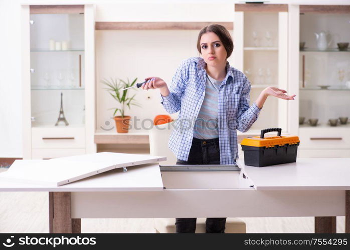 The young beautiful woman assembling furniture at home. Young beautiful woman assembling furniture at home