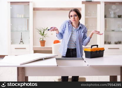 The young beautiful woman assembling furniture at home. Young beautiful woman assembling furniture at home