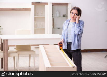 The young beautiful woman assembling furniture at home. Young beautiful woman assembling furniture at home