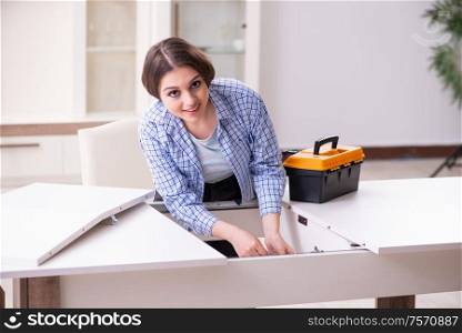The young beautiful woman assembling furniture at home. Young beautiful woman assembling furniture at home