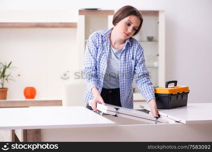 The young beautiful woman assembling furniture at home. Young beautiful woman assembling furniture at home