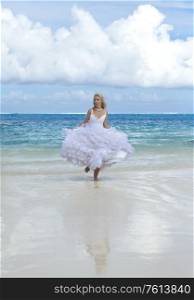 The young beautiful woman in a dress of the bride runs on waves of the sea