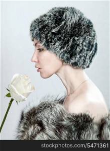The young beautiful woman in fur and with a white rose