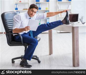 The young businessman doing sports stretching at workplace. Young businessman doing sports stretching at workplace
