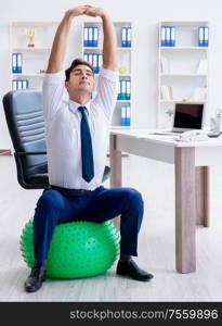 The young businessman doing sports stretching at workplace. Young businessman doing sports stretching at workplace