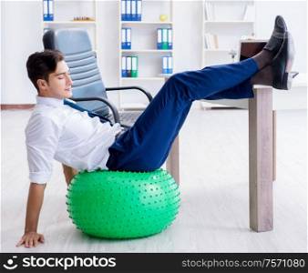 The young businessman doing sports stretching at workplace. Young businessman doing sports stretching at workplace
