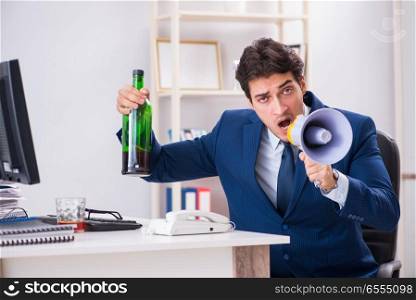 The young businessman employee drinking in the office at desk. Young businessman employee drinking in the office at desk