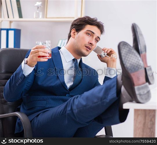 The young businessman employee drinking in the office at desk. Young businessman employee drinking in the office at desk