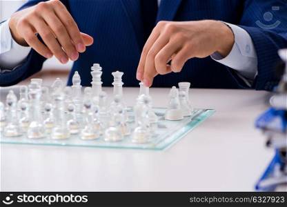 The young businessman playing glass chess in office. Young businessman playing glass chess in office