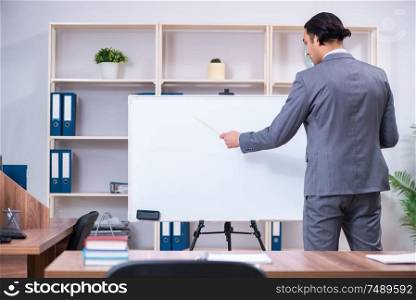 The young businessman standing in front of white board . Young businessman standing in front of white board