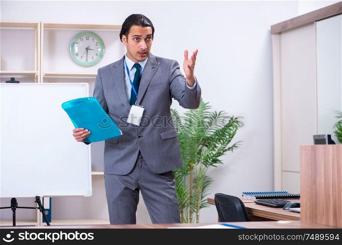 The young businessman standing in front of white board . Young businessman standing in front of white board