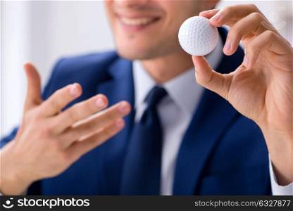 The young businessman with golf ball working in office. Young businessman with golf ball working in office