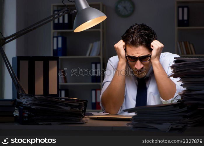 The young businessman working overtime late in office. Young businessman working overtime late in office