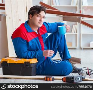 The young carpenter taking break from working with wooden planks. Young carpenter taking break from working with wooden planks