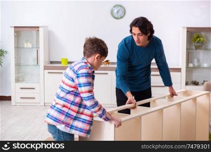 The young carpenter teaching his son . Young carpenter teaching his son