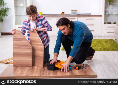 The young carpenter teaching his son. Young carpenter teaching his son